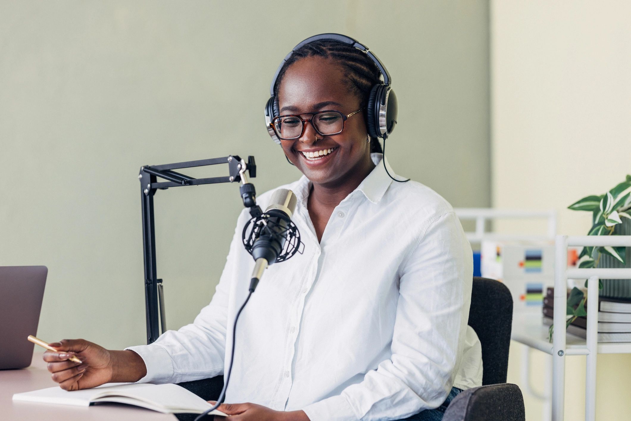 Podcast host recording in a bright modern studio with microphone and headphones
